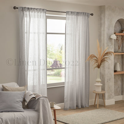 Sheer curtains in a living room with a couch and decorative elements.
