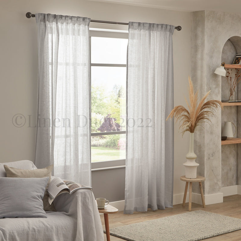 Sheer curtains in a living room with a couch and decorative elements.