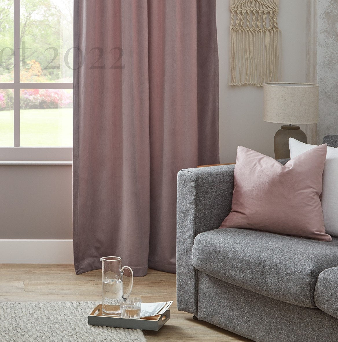 Living room with gray sofa, pink cushions, and a window with curtains.