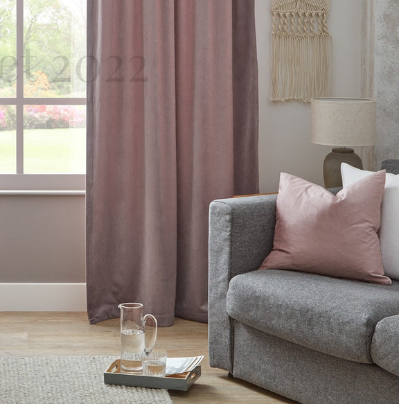 Living room with gray sofa, pink cushions, and a window with curtains.