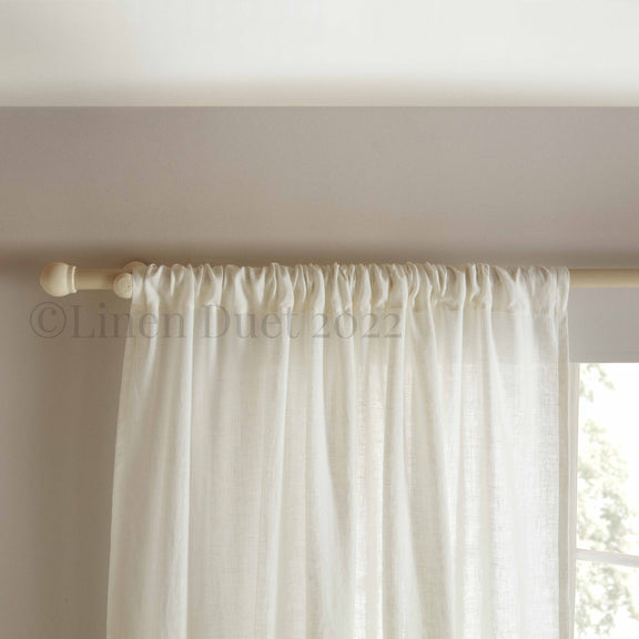 White curtain panel with a wooden rod on a neutral background