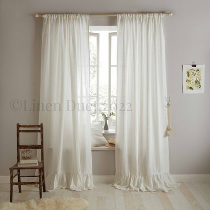 White curtains with ruffled hem in a room with a wooden chair and small table.