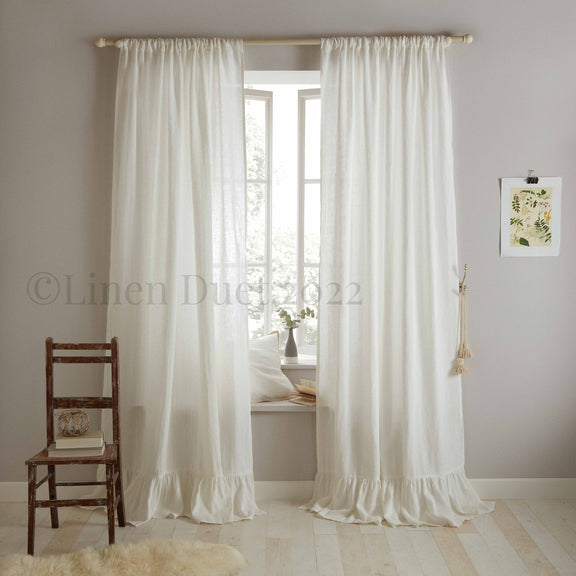 White curtains with ruffled hem in a room with a wooden chair and small table.