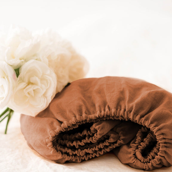 Brown linen duvet cover on a bed with white flowers in the background