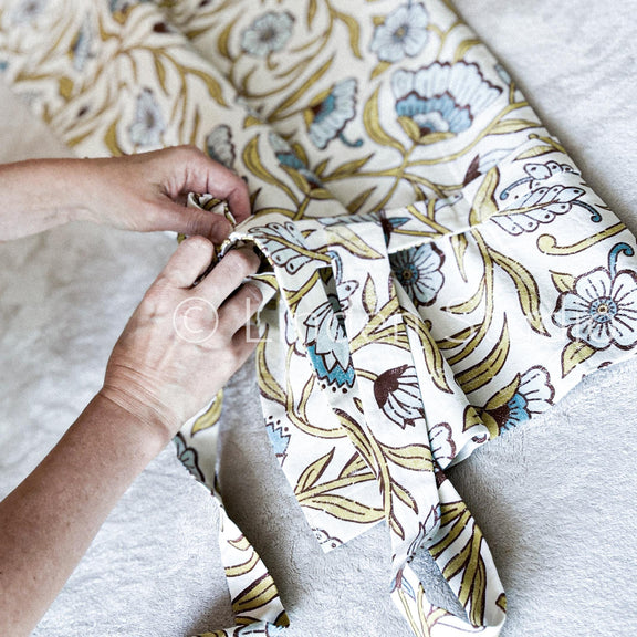 Person holding a piece of floral fabric with a brand logo in the center.
