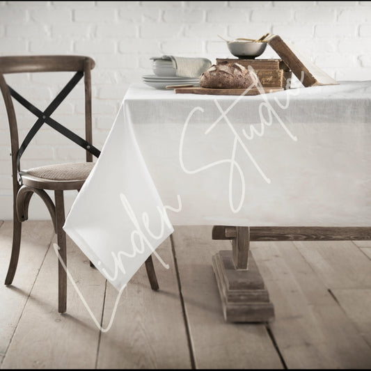 Dining table with a white tablecloth featuring 'Under Study' text, wooden chair, and rustic decor.