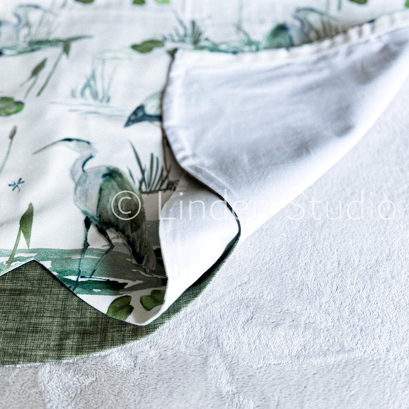 Close-up of a fabric with a nature-themed pattern and white border.