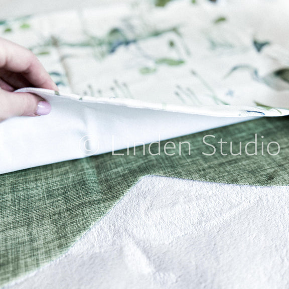 Close-up of fabric with a hand holding it, blurred background with 'Linden Studio' branding.