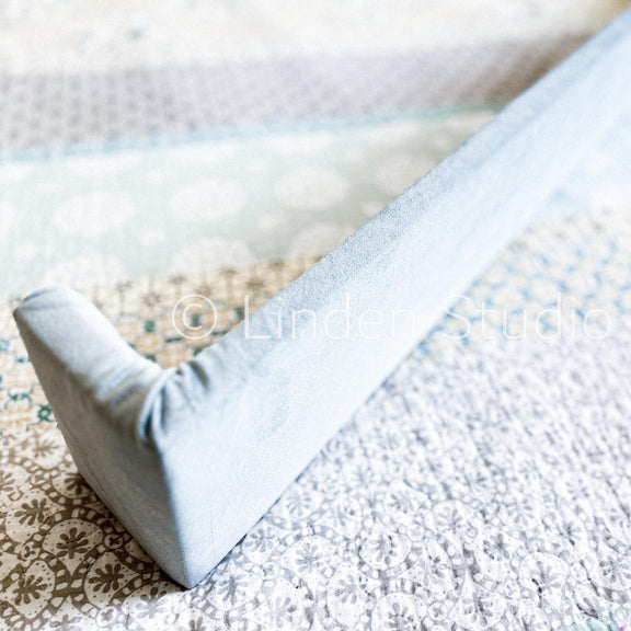 Close-up of a textured surface with a patterned rug and a light blue fabric edge.