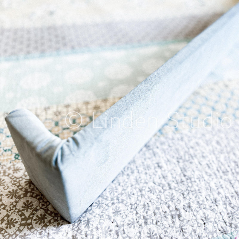 Close-up of a textured surface with a patterned rug and a light blue fabric edge.