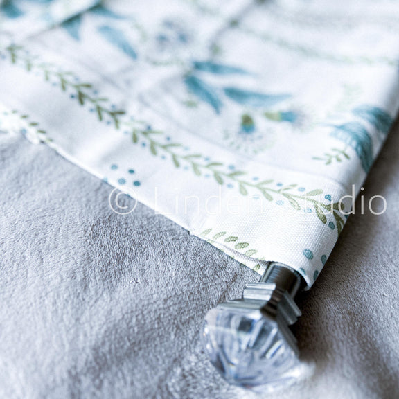 Fabric with floral pattern and decorative clip on a textured surface