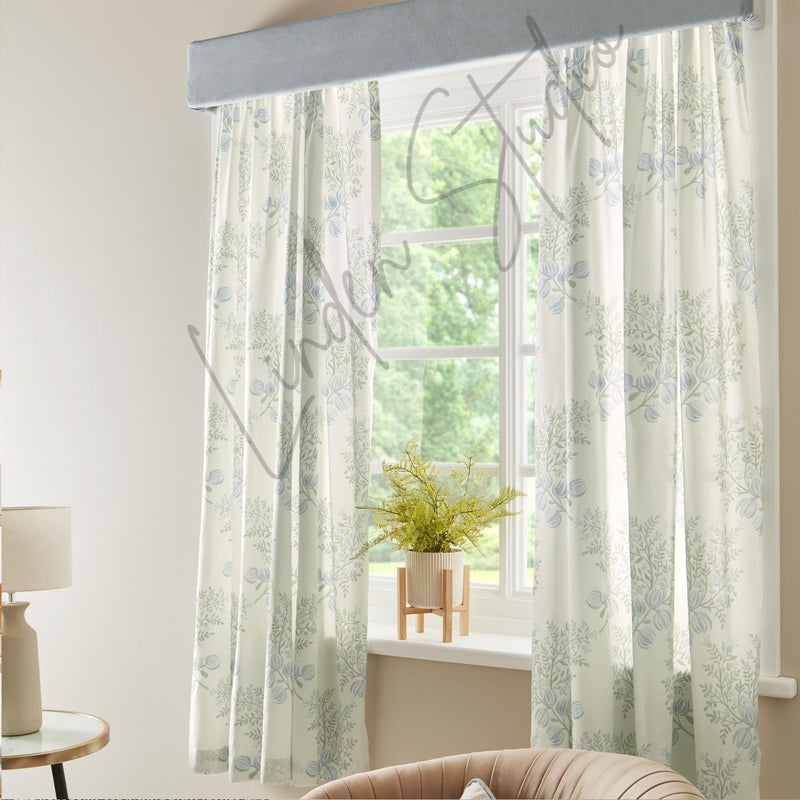 Floral patterned curtains in a room with a lamp and plant.